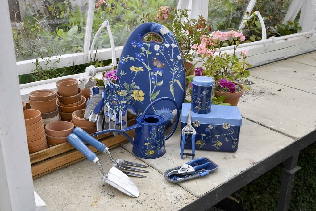 Gardening tools and decorative items on a table outdoors with plants in the background