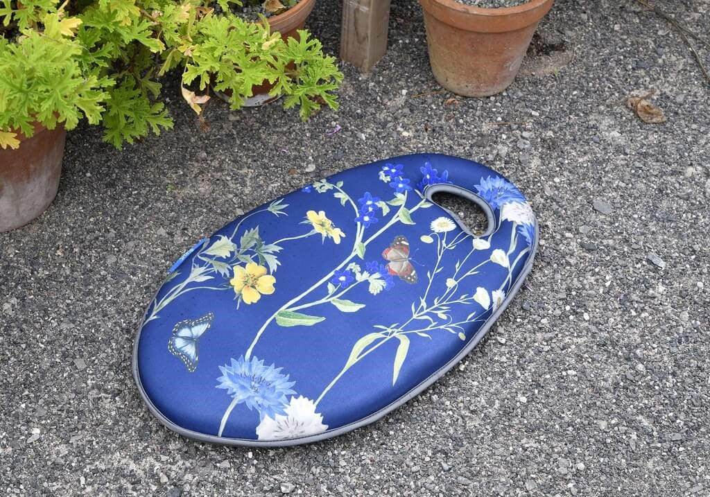 Blue floral-patterned knelling cushion on a concrete surface with plants in the background