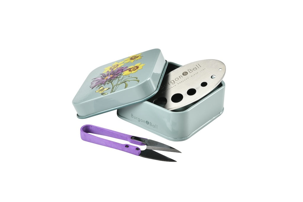 Teal metal tin with floral design, scissors, and 'Bon Cade' branding on a white background