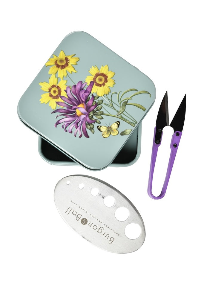 Floral-themed tin with scissors and a tool on a white background