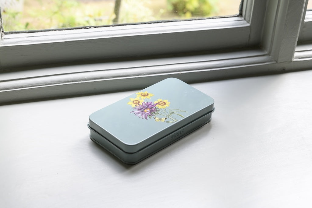 Light blue phone case with floral design on a white surface near a window