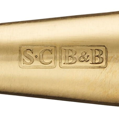 Close-up of a brass object with 'S.C' and 'B&B' branding on a white background