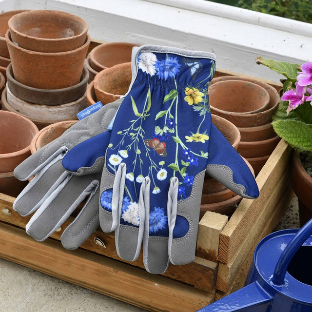 Gardening gloves with floral design on a tray with pots and a watering can.