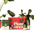 We the Wild plant care essentials pack including a red box labeled 'Plant Lover', bottles wth Support, grow and protect in green and white design 